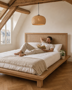 Lit plateforme Saint-Paul en chêne massif avec tête de lit en cannage — mise en scène dans un appartement sous les toits — Maison Mansarde