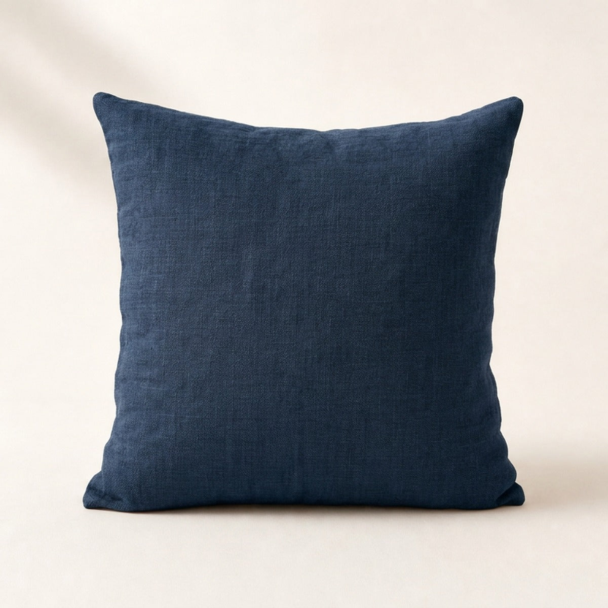 Coussin Buttes-Chaumont en lin lavé coloris bleu nuit, de face sur fond crème