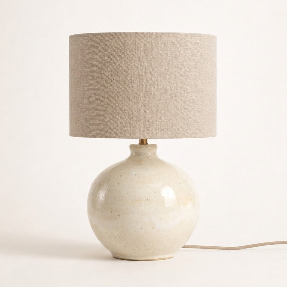 Lampe à poser Ménilmontant en céramique coloris blanc cassé, pied rond et abat-jour en lin, sur fond crème