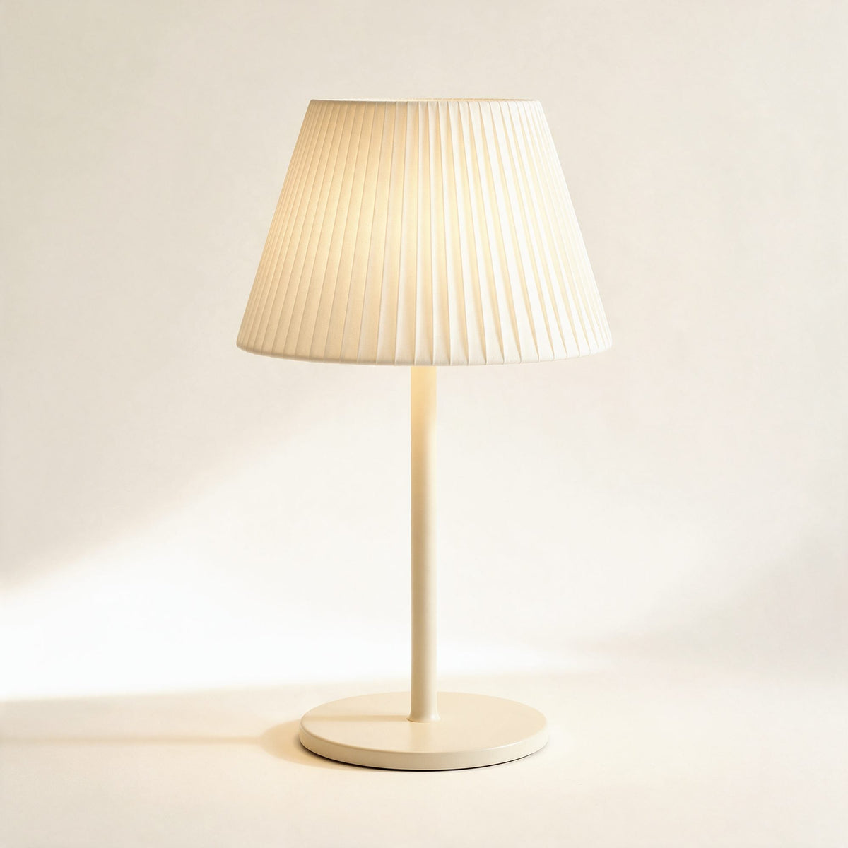 Lampe sans fil Solférino crème à abat-jour plissé, allumée, sur fond crème