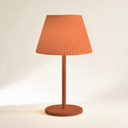 Lampe sans fil Solférino terracotta à abat-jour plissé, allumée, sur fond crème