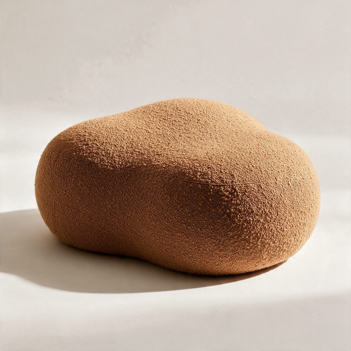 Pouf Nuage en bouclette caramel au contour organique, sur fond crème