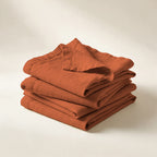 Serviettes de table Buci en lin lavé terracotta, pliées en pile, sur fond crème